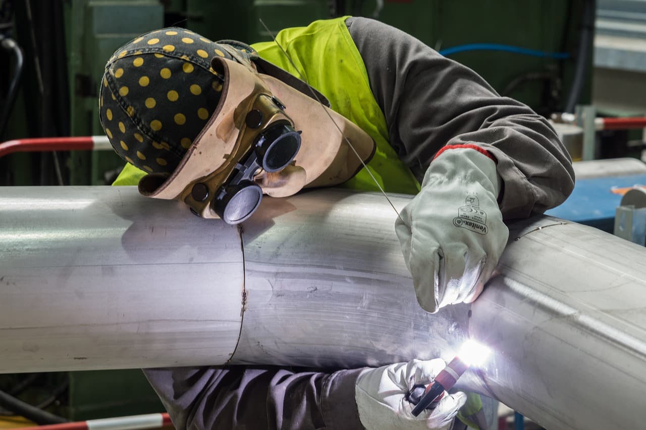 Welder in a hood joining a large steel pipe